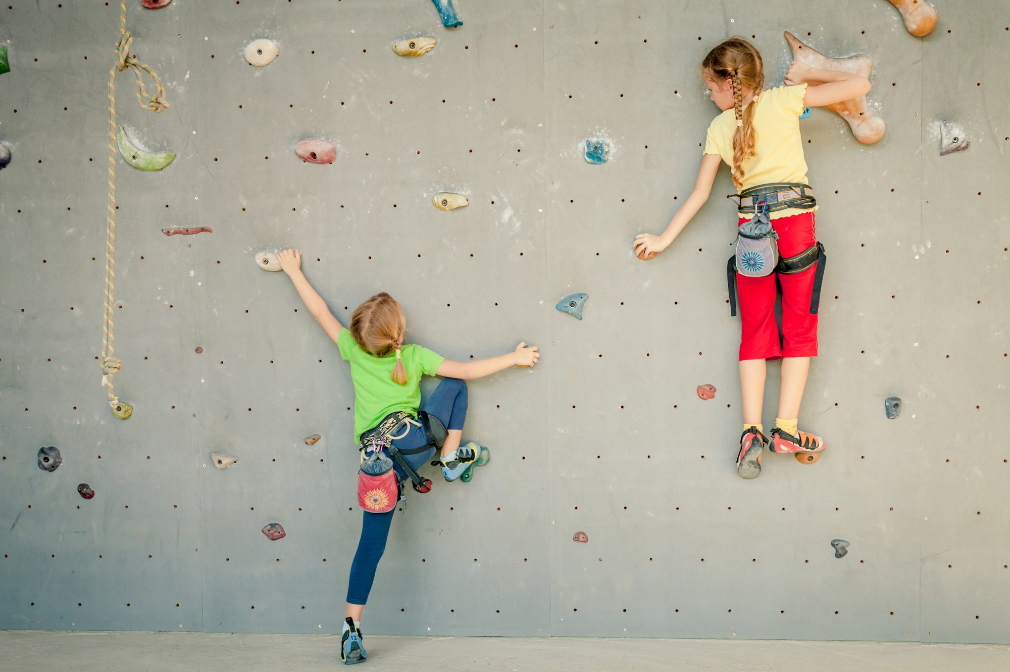 two little girls climbing a rock wall